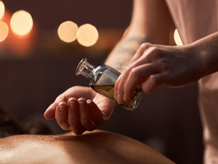 Óleo de massagem ao lado de toalhas dobradas